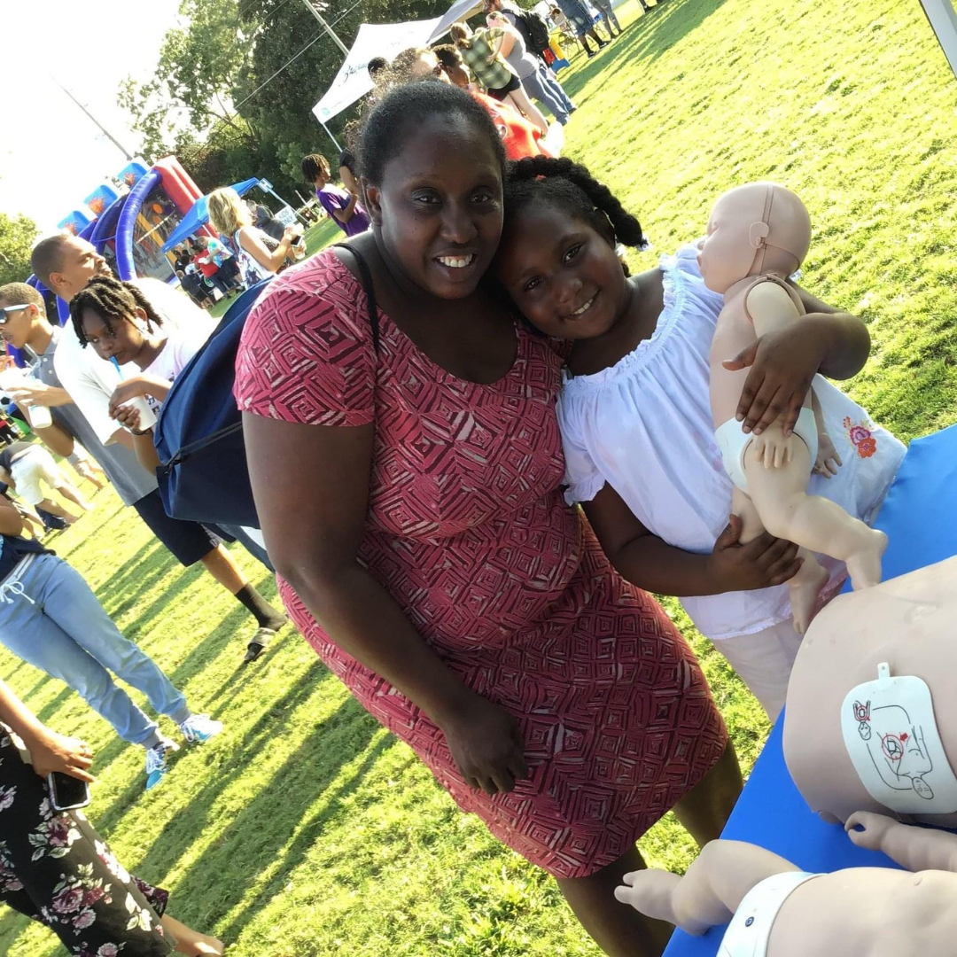 mom and daughter smiling. child holding baby mannequin doll.